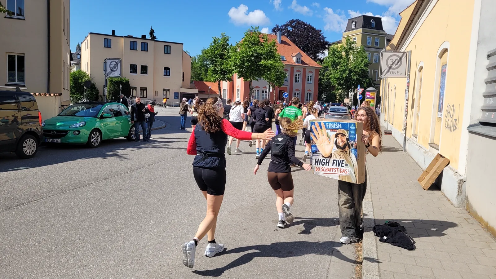 Läuferinnen strecken im Vorbeilaufen die Hand nach dem High-Five-Schild aus
