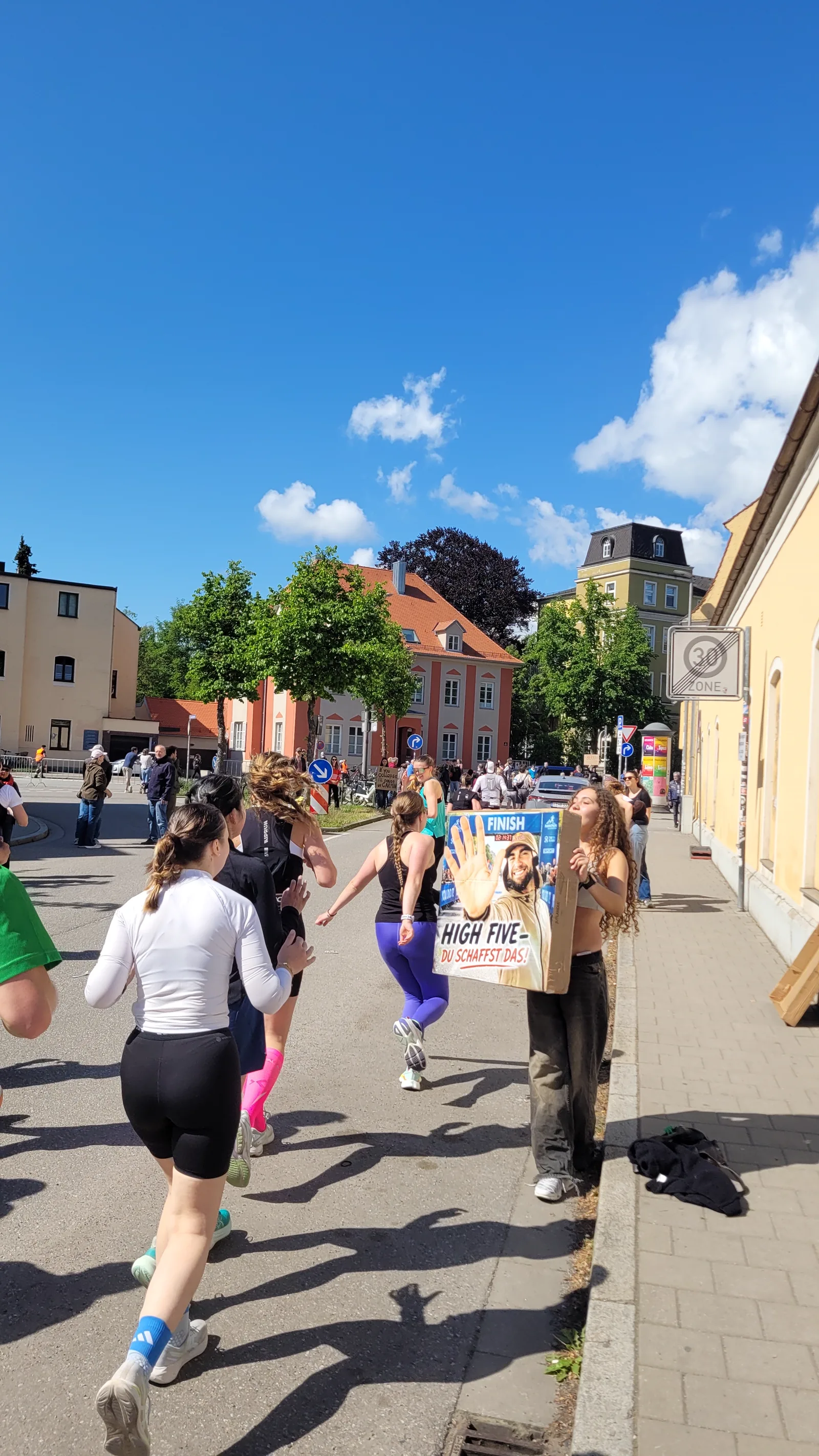 Läuferin springt beim Regensburg-Marathon 2026 hoch, um das gedruckte High-Five-Schild abzuklatschen