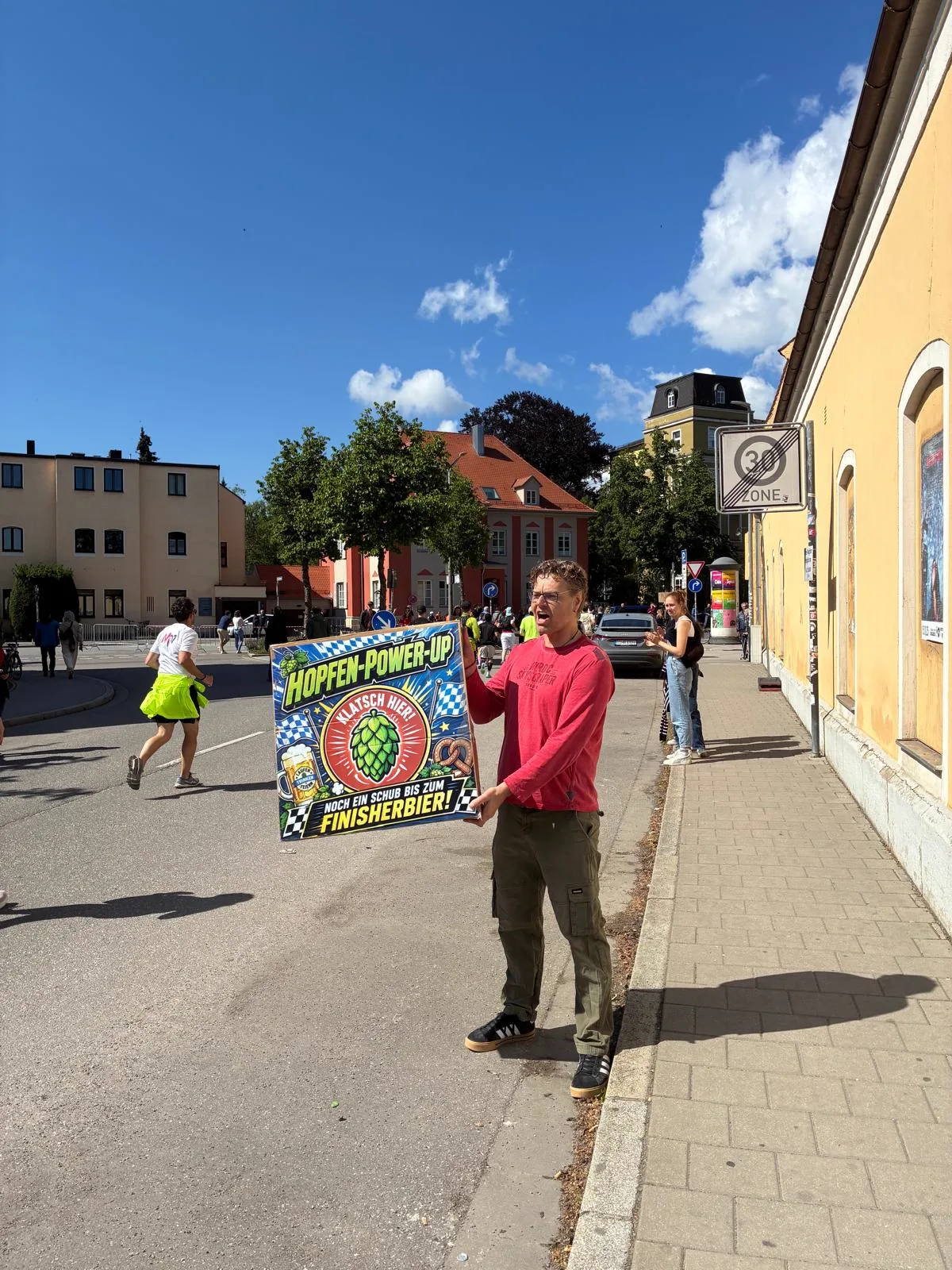 Martin feuert mit dem Hopfen-Power-Up-Schild lautstark die vorbeilaufenden Marathonläufer an